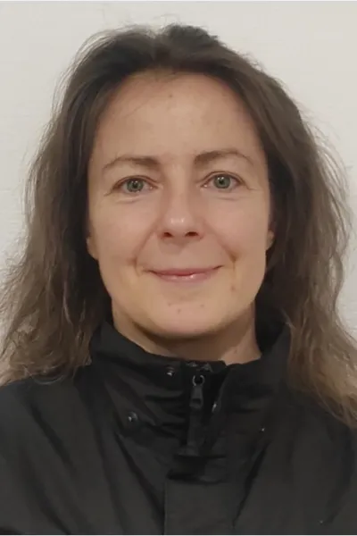 A képen Karácsony Orsolya látható, fekete felsőben, mosolyog a kamerába.